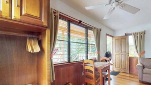 A room with a dining table, chairs, a ceiling fan, wooden cabinets, and a window with blinds. - Charming cabana with a porch, hammock, strong WiFi, and a shared pool & grill (Hopkins)