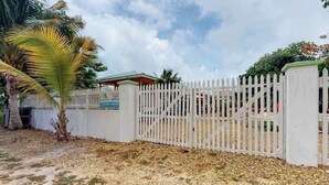 A gated property with a white fence, a palm tree, and a building with a green roof. - Charming cabana with a porch, hammock, strong WiFi, and a shared pool & grill (Hopkins)