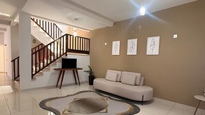 Una sala de estar moderna con una escalera, un sofá, una mesa de centro y obras de arte en la pared.