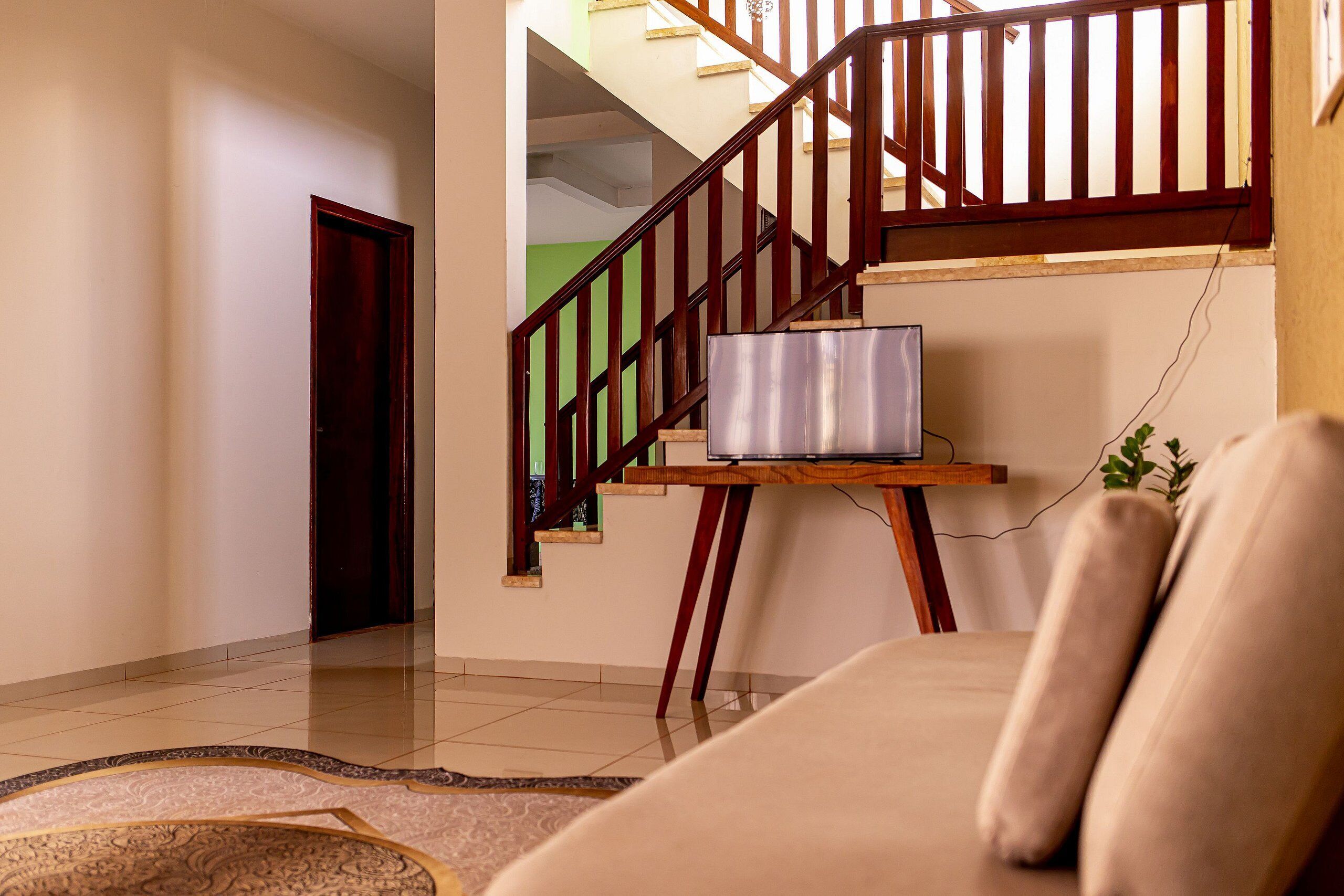 A staircase with wooden railings, a sofa, and a television on a wooden stand.