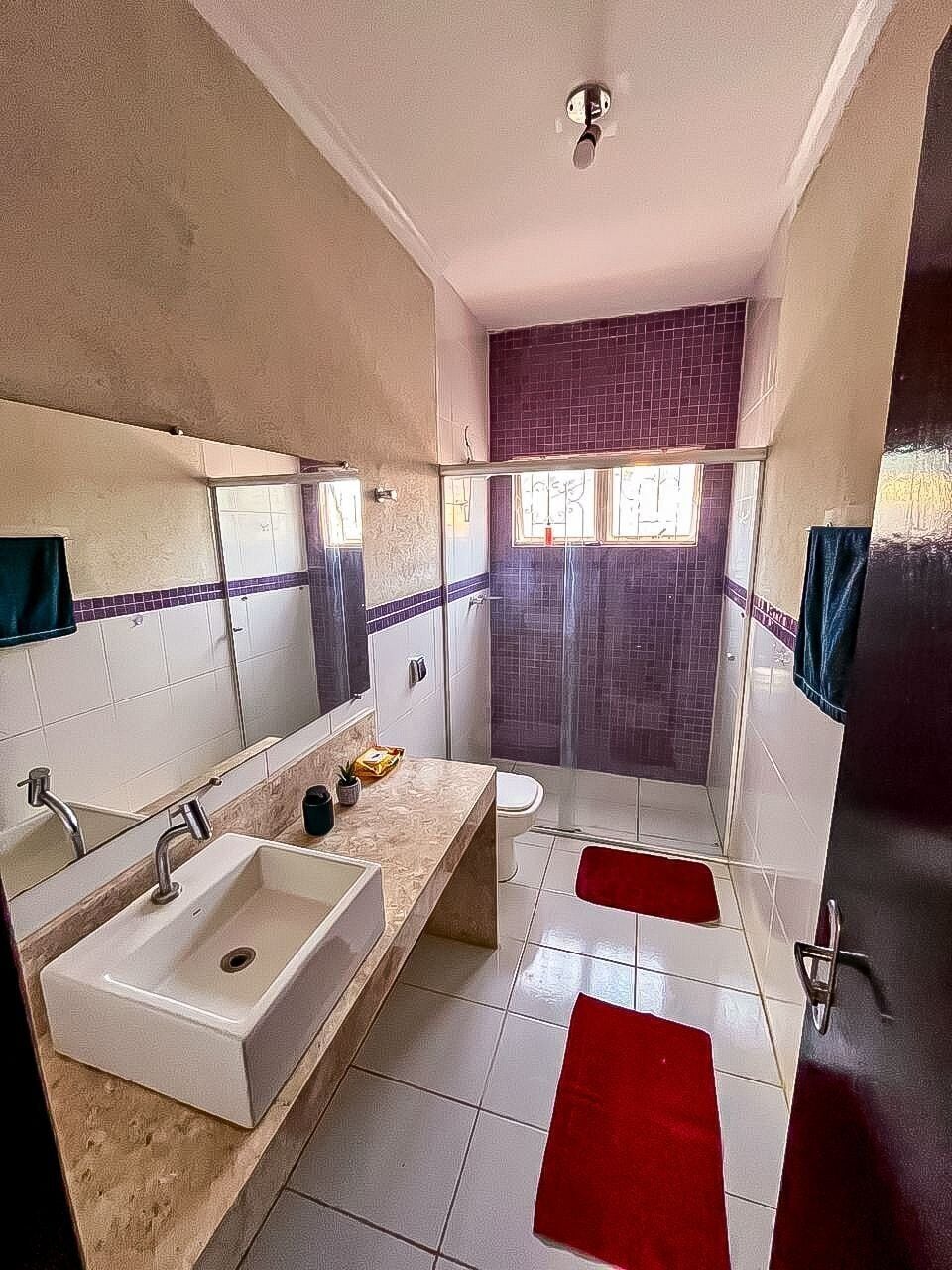 Une salle de bain avec une douche, deux lavabos, des toilettes et un miroir.