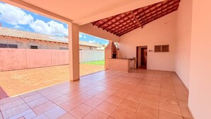 Un espacio habitable diáfano con suelo de baldosas, chimenea de ladrillo y vistas a un barrio residencial.