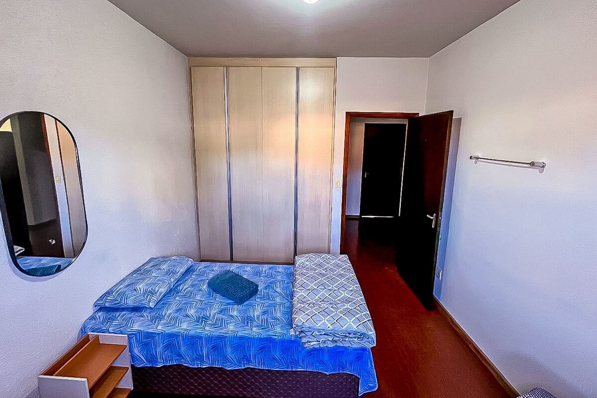 A bedroom with a bed, a wardrobe, a mirror, and a door.