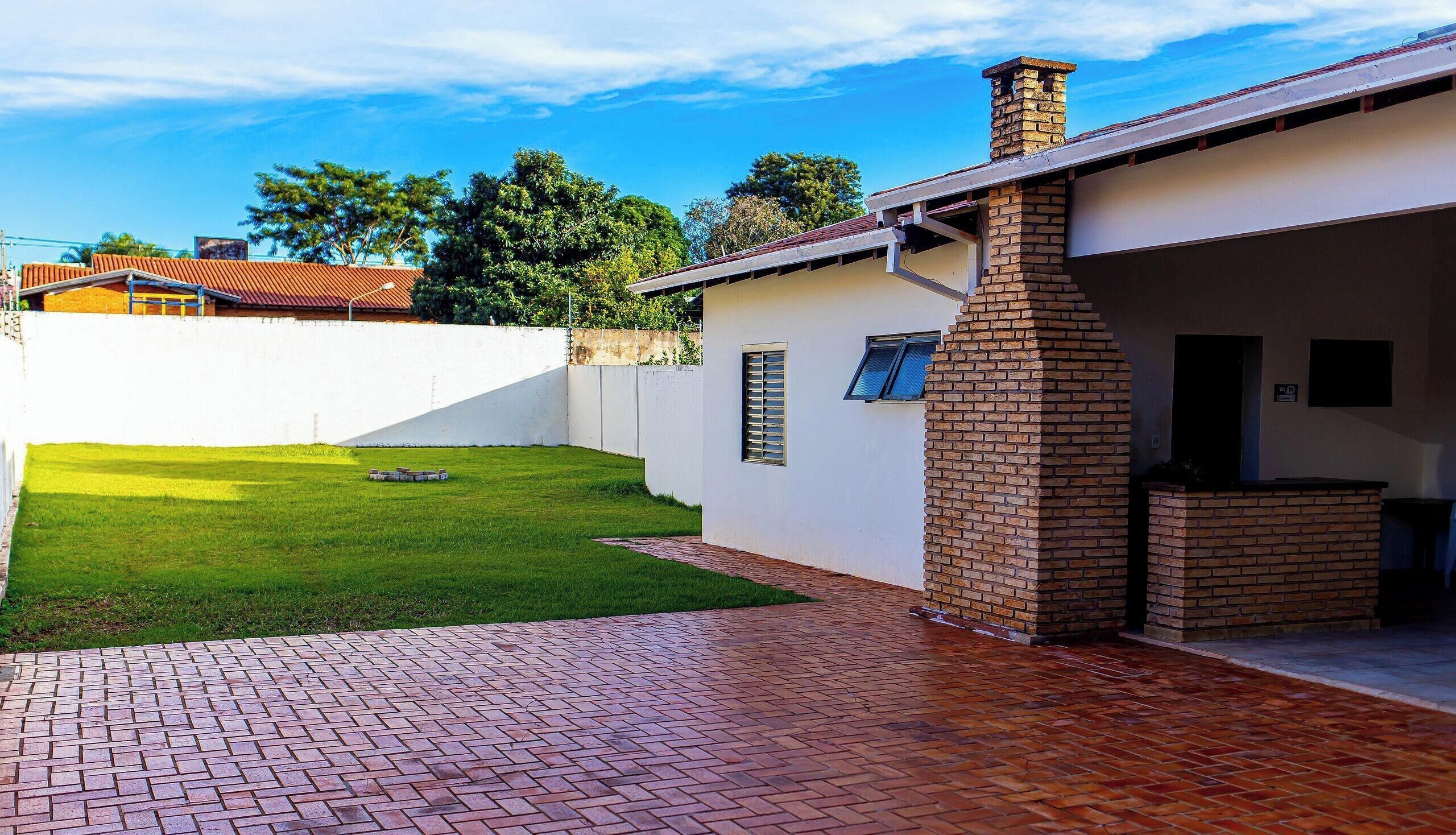 A residential property with a paved driveway, a well-maintained lawn, and a brick chimney.