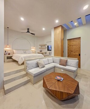 Een moderne slaapkamer met een groot bed, een bank, een salontafel en een televisie.