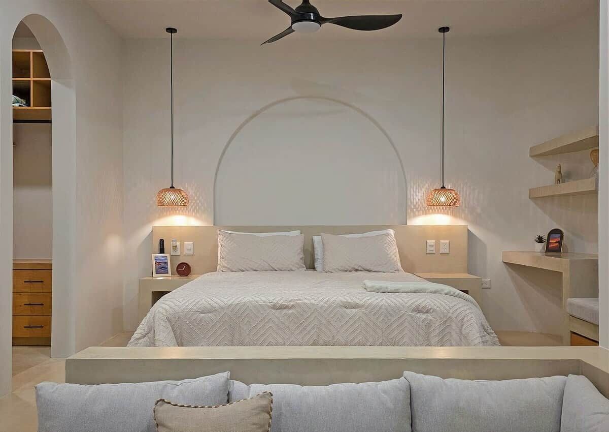 Ein Schlafzimmer mit einem Bett, zwei Nachttischen, einem Deckenventilator und Wandleuchten.