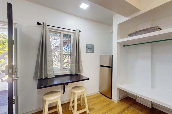 A kitchen with a window, a refrigerator, and a shelf. - Charming island cabana with central AC, bikes & picnic area near beach (Caye Caulker)