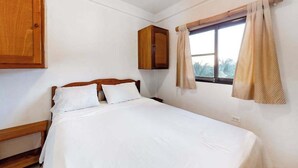 A bedroom with a bed, wooden wardrobe, and a window with curtains. - Unit 8 Muyal Suite at Mayan Falls (Caye Caulker)