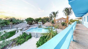 A resort with a swimming pool, palm trees, and a thatched-roof structure. - Unit 8 Muyal Suite at Mayan Falls (Caye Caulker)