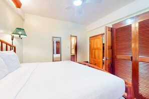 Een hotelkamer met een bed, een plafondventilator, een deur en een lamp aan de muur.
