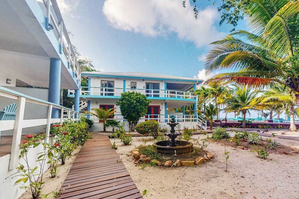 A hotel with a wooden deck, a fountain, and tropical plants.
