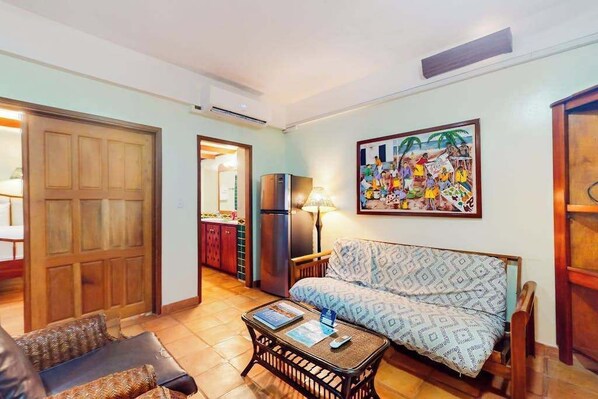 Een woonkamer met een bank, een salontafel en een schilderij aan de muur.