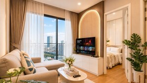 Ein modernes Wohnzimmer mit einer Couch, einem Couchtisch, einem Fernseher und einem Balkon mit Blick auf die Stadt.