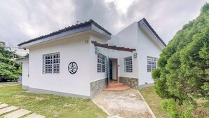 Un bâtiment à deux étages, à l’extérieur blanc, avec un toit recouvert de tuiles et un petit porche à l’avant.