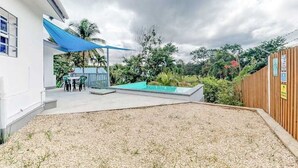 Un espace extérieur moderne doté d’une piscine, d’un coin salon couvert et d’une clôture en bois.
