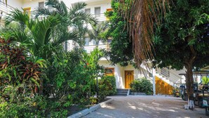 A hotel courtyard with a central staircase, surrounded by lush greenery and a covered seating area. - Relaxing condo with shared pool, ocean views, partial AC & WiFi (San Pedro)