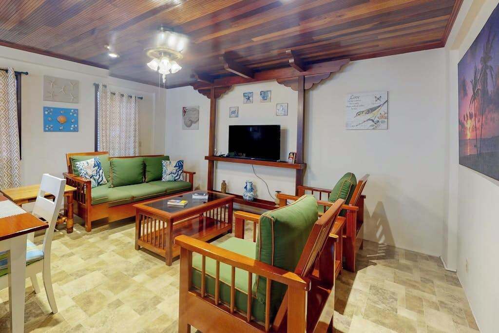 Een woonkamer met een bank, stoelen, een salontafel, een televisie en kunstwerken aan de muur.