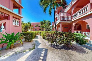 Un patio con un sendero, palmeras y un edificio con balcones.