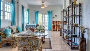 Un vaste espace de vie aménagé avec des meubles en osier, une table à manger et une bibliothèque.