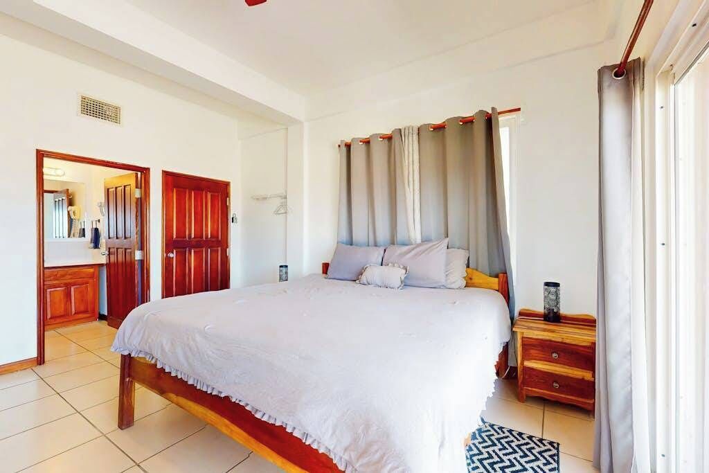 A bedroom with a bed, wooden nightstands, a mirror, and a door leading to a bathroom.