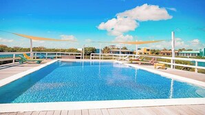 Una piscina rectangular con cubierta de madera y barandillas blancas, rodeada por una cerca blanca.