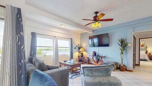 A living room with a ceiling fan, a flat-screen TV, and a large window. - Waterfront villa with outdoor pool, washer dryer, & central AC (San Pedro)