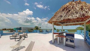 A beachside lounge with lounge chairs, a thatched-roof structure, and a grill. - Waterfront villa with outdoor pool, washer dryer, & central AC (San Pedro)