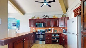 A kitchen with wooden cabinets, a microwave, an oven, and a refrigerator. - Steps from the sea apartment with shared pool & ocean-view balcony (San Pedro)