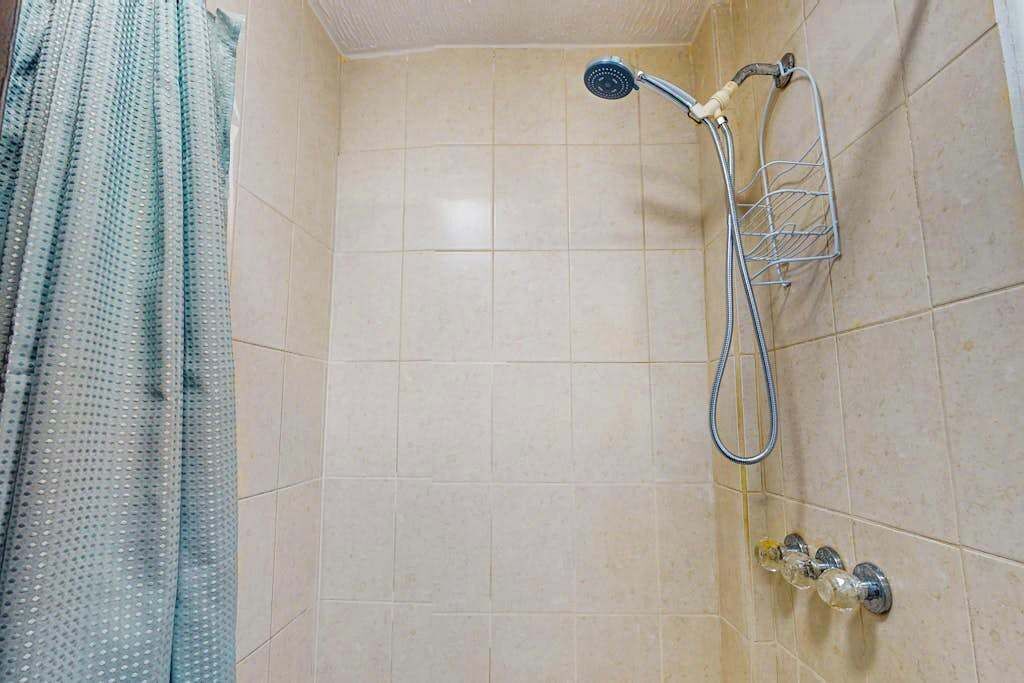 Une douche équipée d’un pommeau de douche à main, d’un sèche-mains mural et d’un porte-savon.