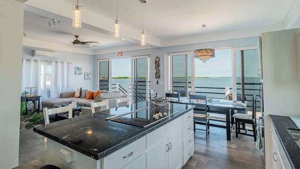 A modern kitchen with a large island, pendant lights, and a view of the ocean. - Amazing 2 story oceanfront house with pool, balcony, central AC, & WD (San Pedro)