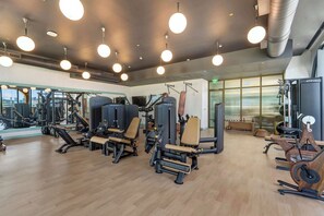 A gym with exercise equipment, large windows, and a wooden floor. - Modern Wynwood with Rooftop Pool  (Miami)