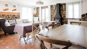 A dining area with a large wooden table and chairs, a stone wall, and a fireplace. - Premium Rural House · Garden & Barbecue (Garray)