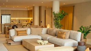 A modern living room with a sectional sofa, a coffee table, and a dining area with chairs. - Anera | Private Oceanfront Garden (Playa Blanca)