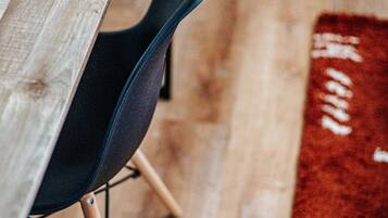 A wooden table with a black chair, a red rug, and a wooden floor.