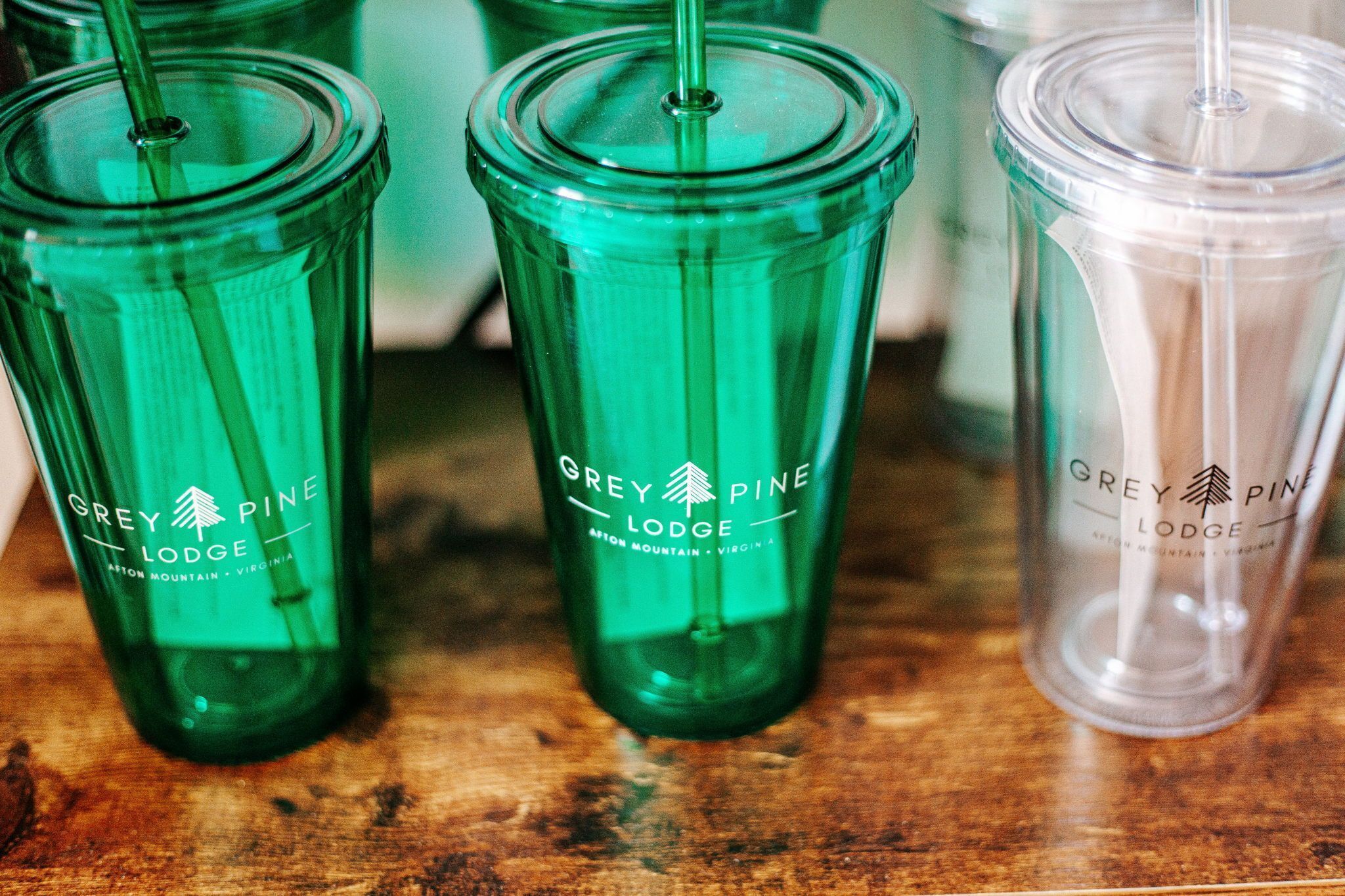 Tre glas med Grey Pine Lodge logo på en træoverflade.