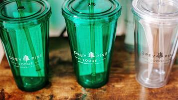 Tre glas med Grey Pine Lodge logo på en træoverflade.