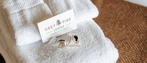 A neatly folded white towel with a tag labeled 'Grey Pine Lodge' on a textured brown surface.