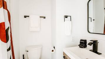 A bathroom with a toilet, a towel rack, a sink with a mirror, and a black towel labeled 'Makeup'.