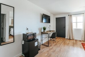 Un espacio habitable compacto con kitchenette, televisión de pantalla plana, escritorio y una silla.