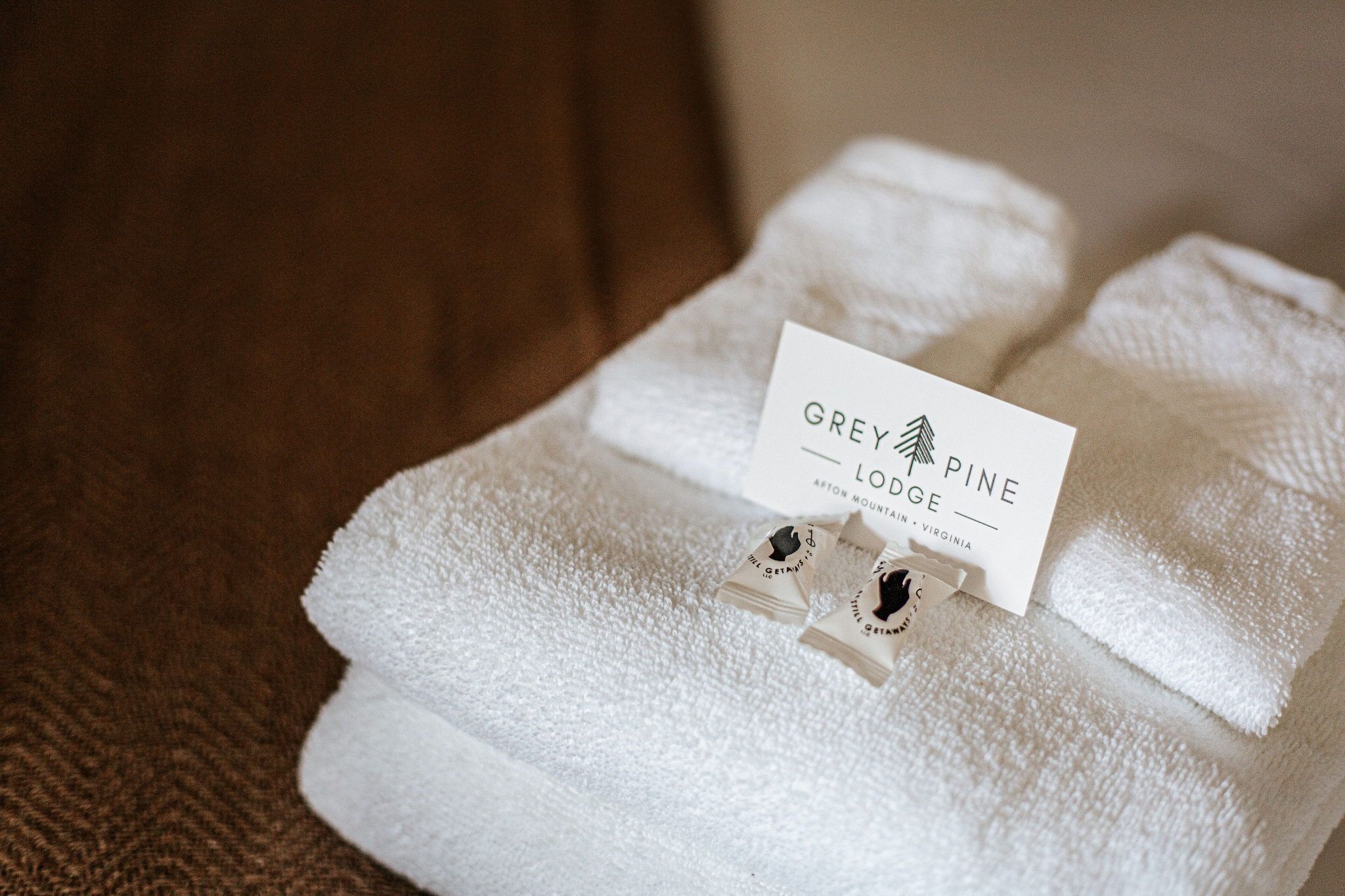 A neatly folded white towel with a card labeled 'Grey Pine Lodge' and a small tag.
