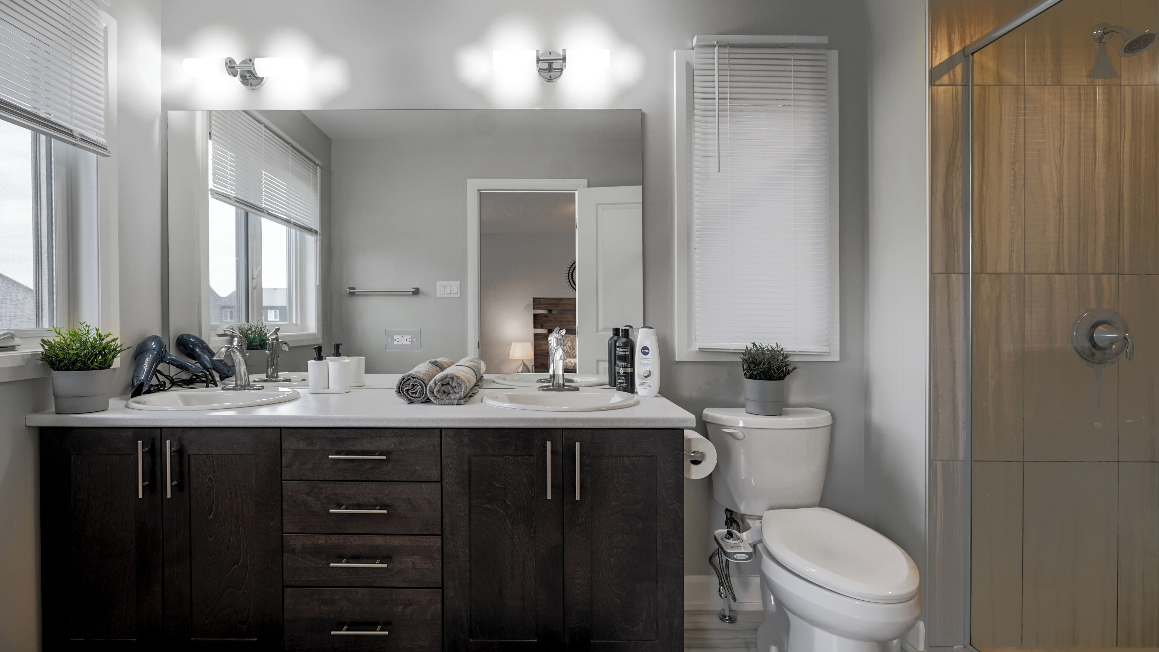 Une salle de bain moderne équipée d’un meuble-lavabo, de toilettes et d’une douche.