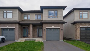 A two-story residential building with a brick facade, two garage doors, and a small front porch.