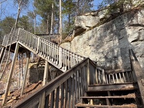 A wooden staircase leading up a rocky hillside, surrounded by trees.