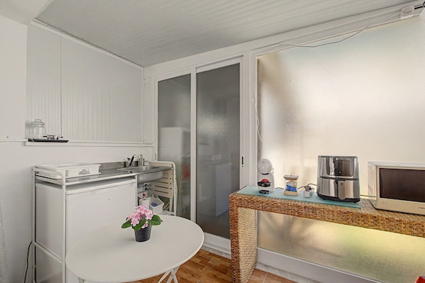 A compact kitchenette with a sink, a small table with a potted plant, a coffee maker, and a microwave.