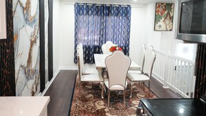 Een eetruimte met een witte tafel, stoelen en een tapijt met dessin.