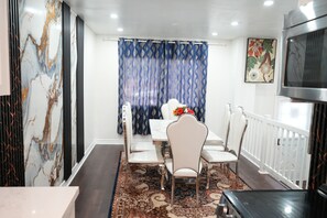 A dining area with a white table, chairs, and a patterned rug. - Bright 3BR Home | Explore Niagara & Beyond (Welland)