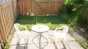 Een terras met twee witte plastic stoelen en een ronde tafel.