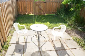 A patio with two white plastic chairs and a round table. - Bright 3BR Home | Explore Niagara & Beyond (Welland)