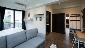 A modern hotel room with a sofa, a dining table, a small kitchen area, and a balcony with a view. - Letaotao Inn (Ji'an)