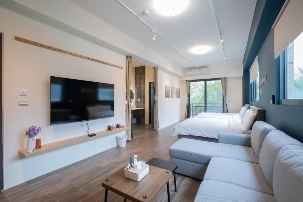 Una habitación de hotel moderna con televisión de pantalla plana, sofá, cama y una mesita.